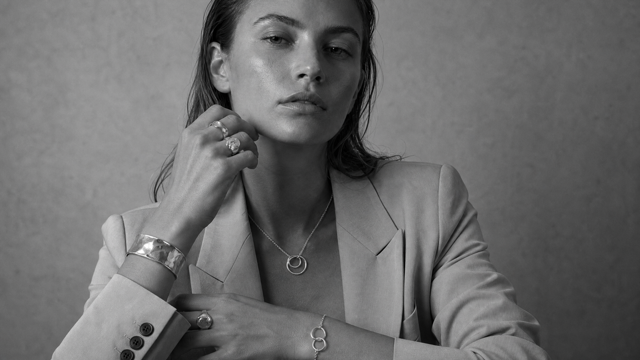 Woman wearing layered sculptural jewellery in black and white editorial styling.