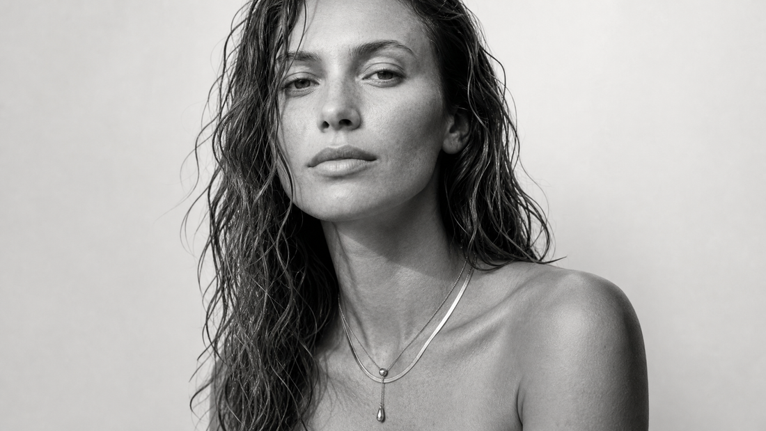 Woman wearing layered necklaces in black and white styling.