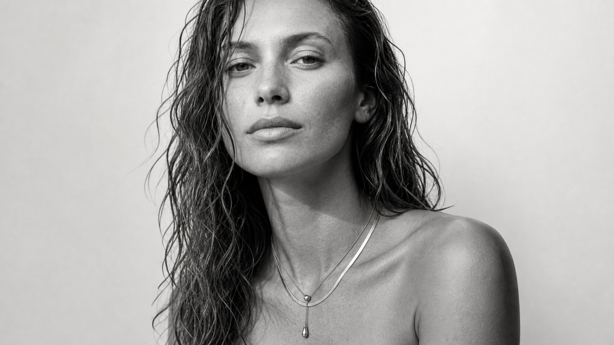 Woman wearing layered necklaces in black and white styling.