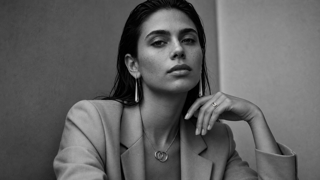 Woman wearing minimal sculptural jewellery in black and white editorial styling.