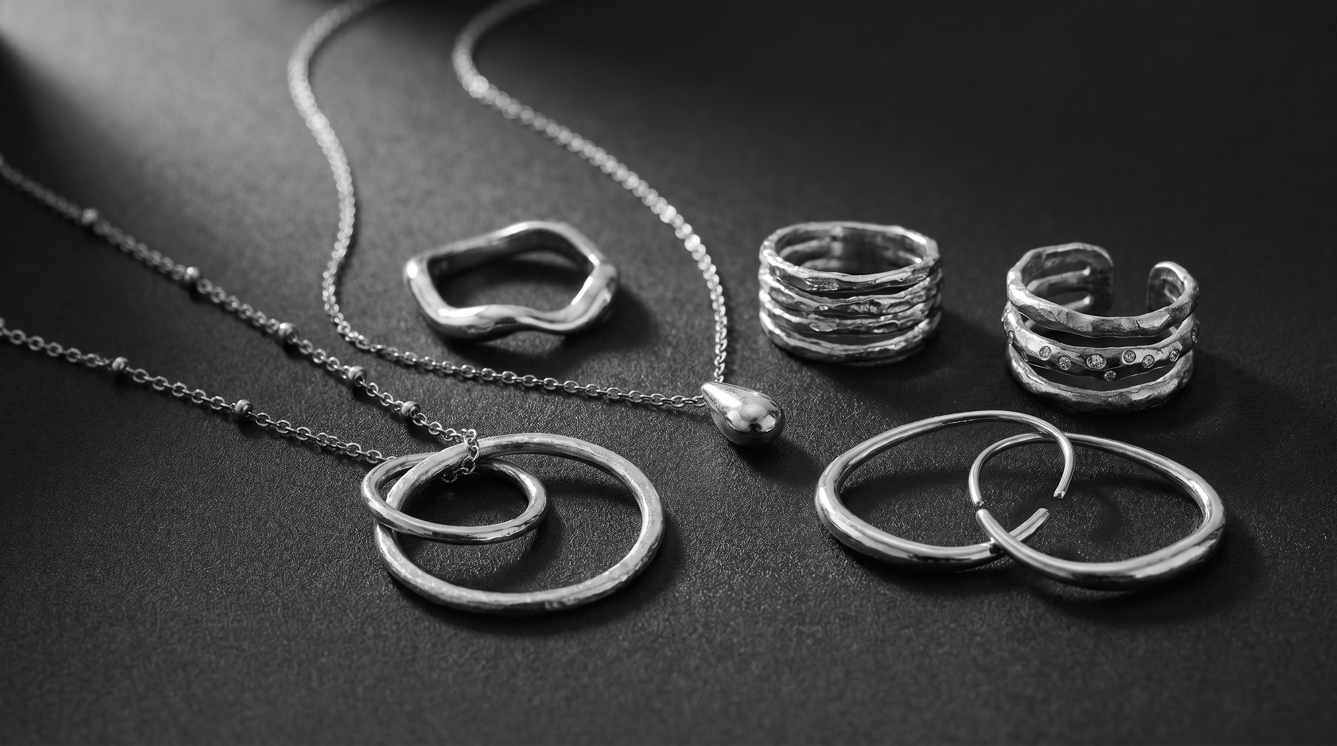 Layered textured jewellery in black and white close-up photography.