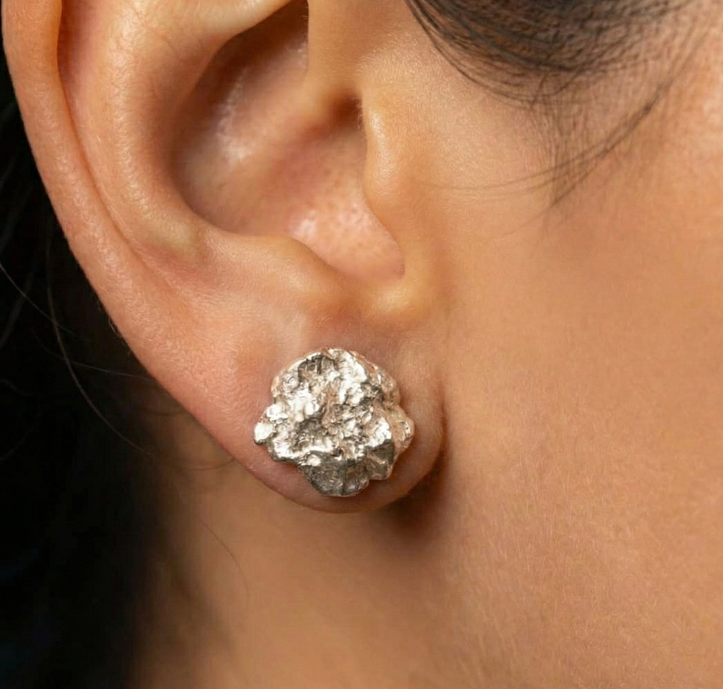 Close-up of an ear wearing a silver stud earring.