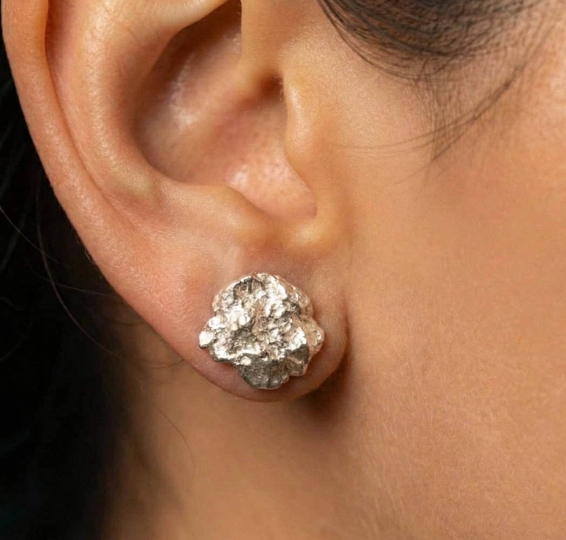 Close-up of an ear wearing a silver stud earring.
