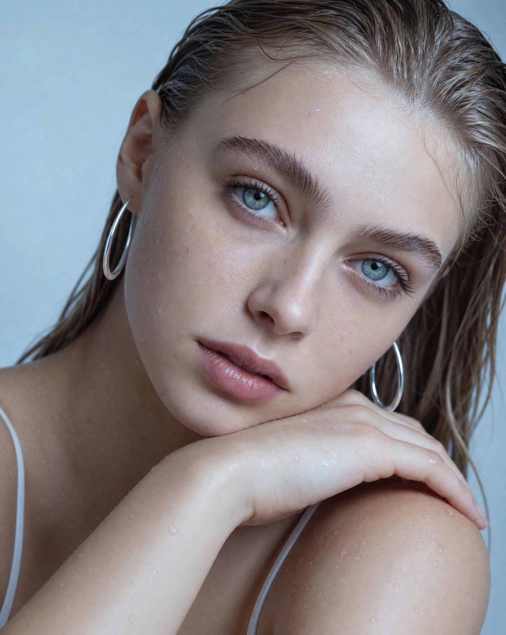 Woman with refined Silver hoop earrings and a white top against a light background