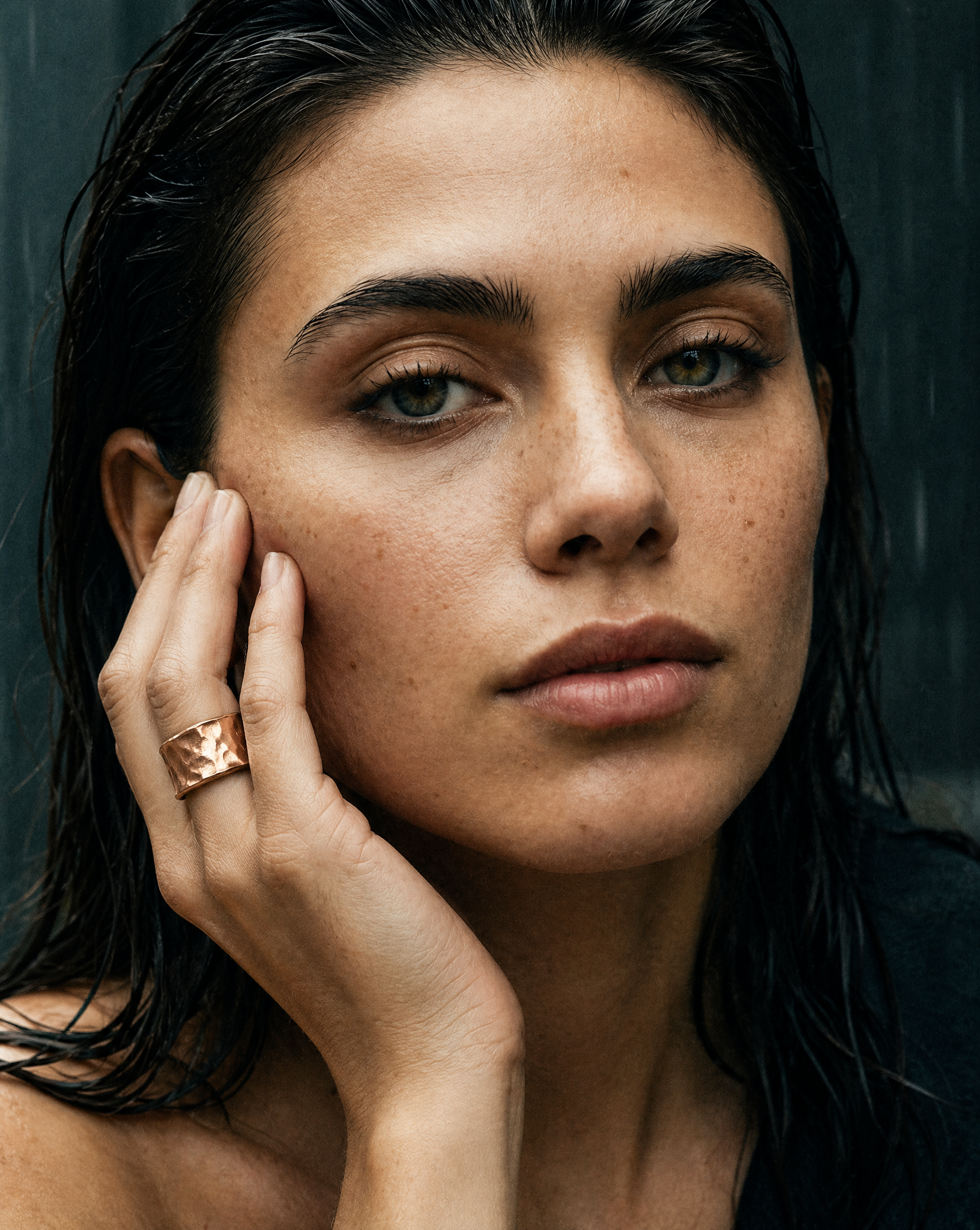 Tactile rose gold ring on a woman's hand on a blurry background.