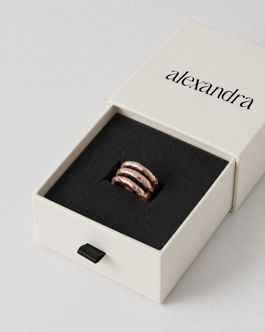 Earthy rose gold Ring in a 'alexandra' branded box on a light gray background