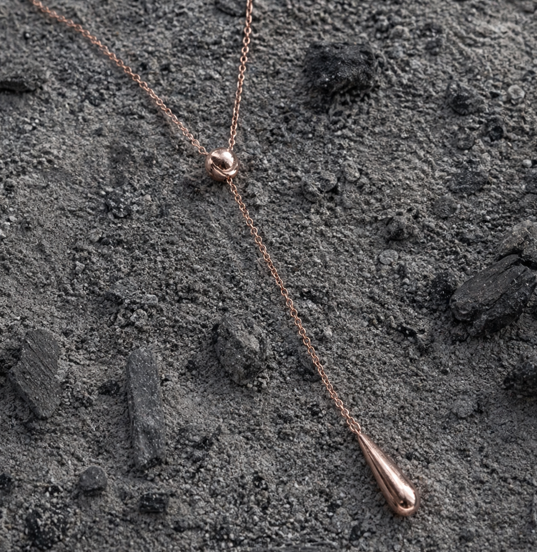 Rose gold necklace Australia. Lariat Necklace, pendant on a textured dark surface