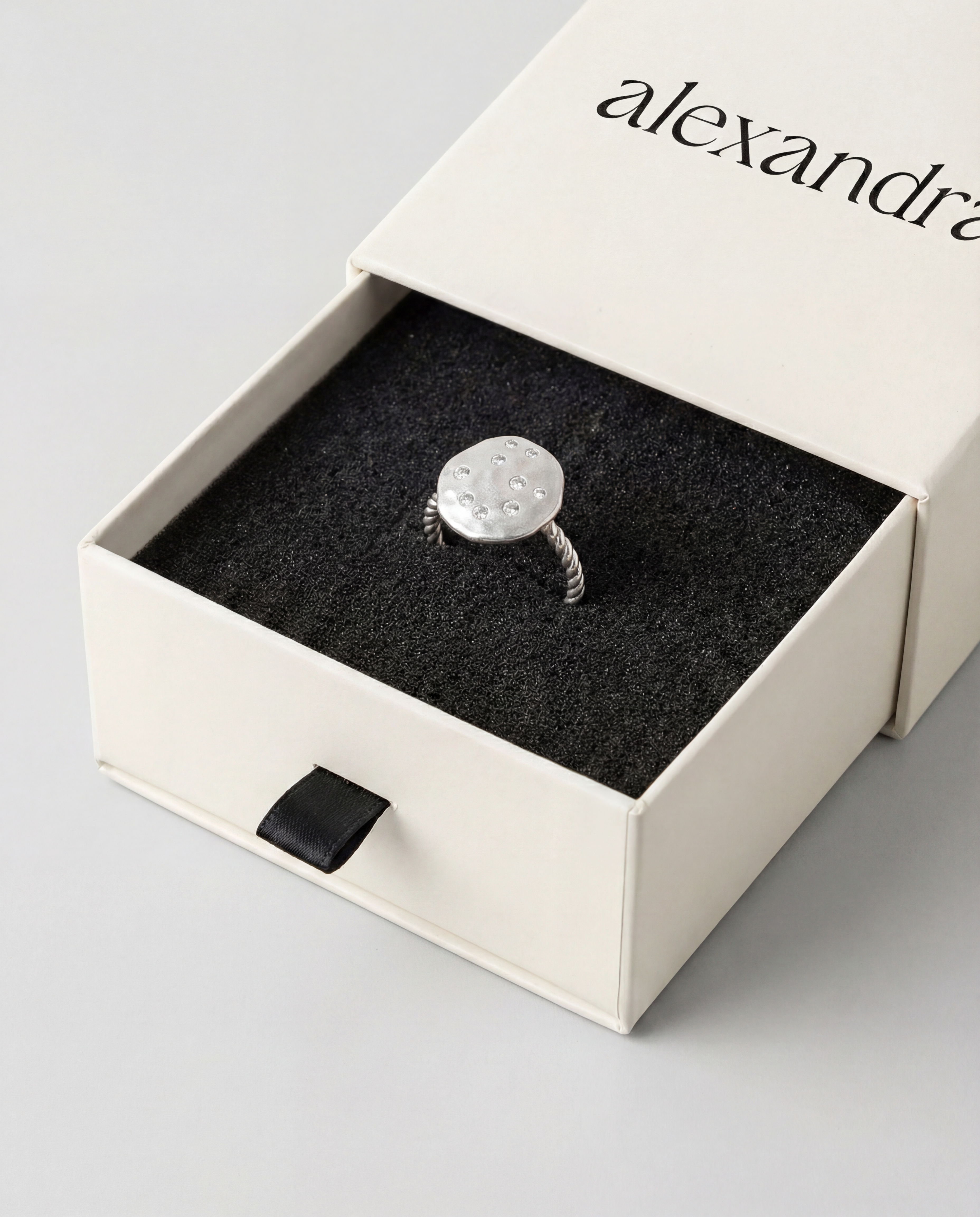 Silver ring in a branded box on a light gray background