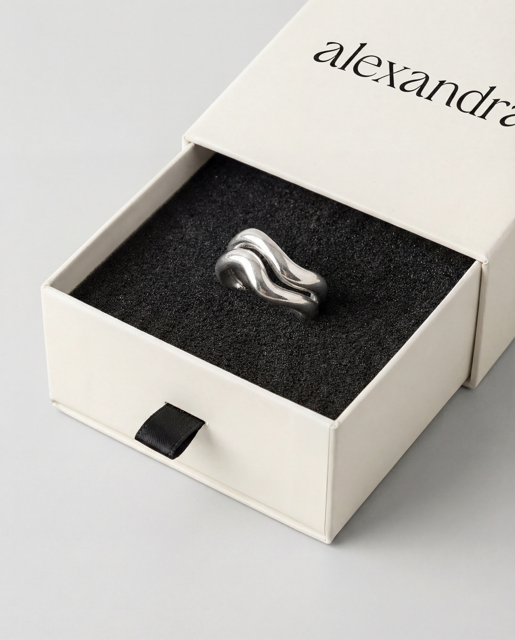 Silver ring in a branded box on a light gray background