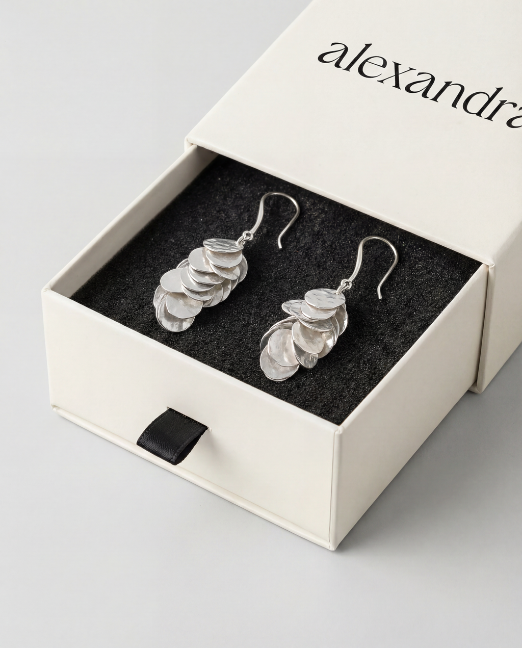 Silver cluster earrings in a branded box on a light gray background