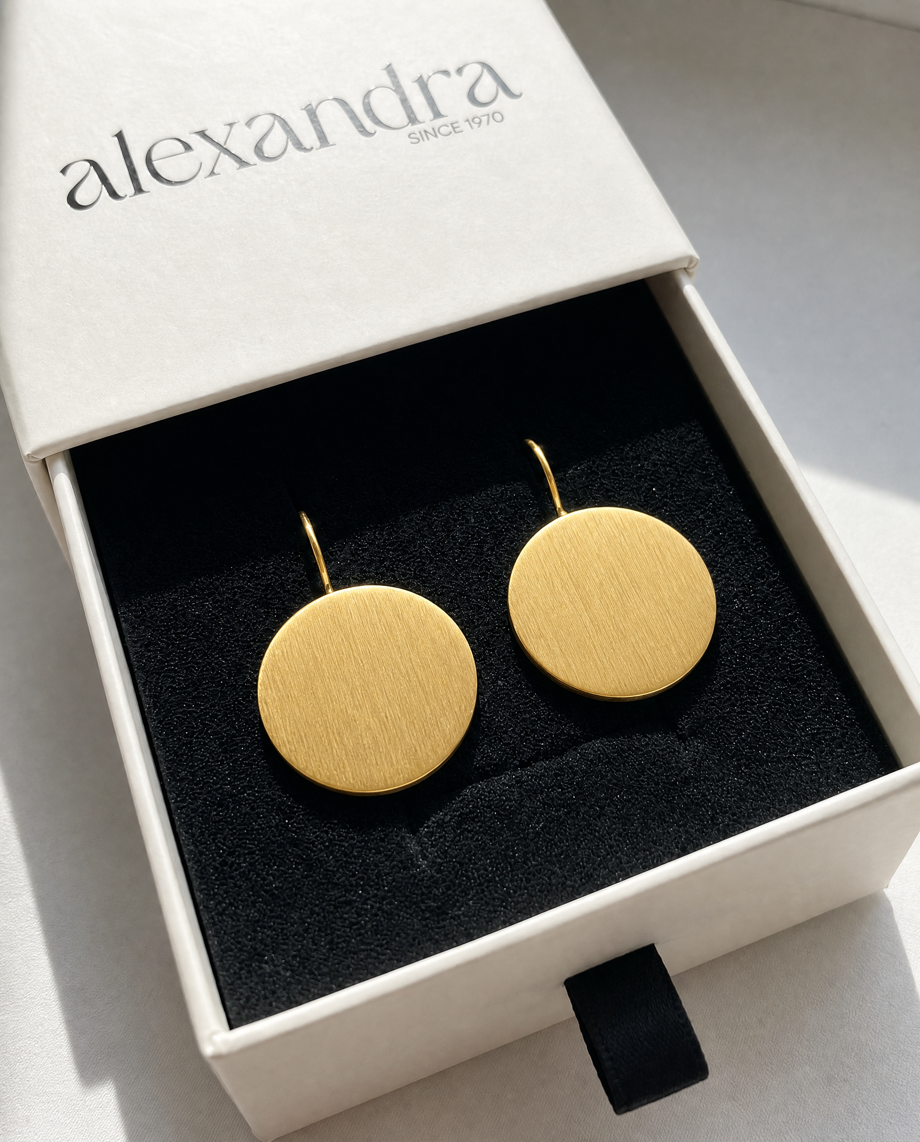 Sculptured Gold earrings in a 'alexandra' branded box on a light background