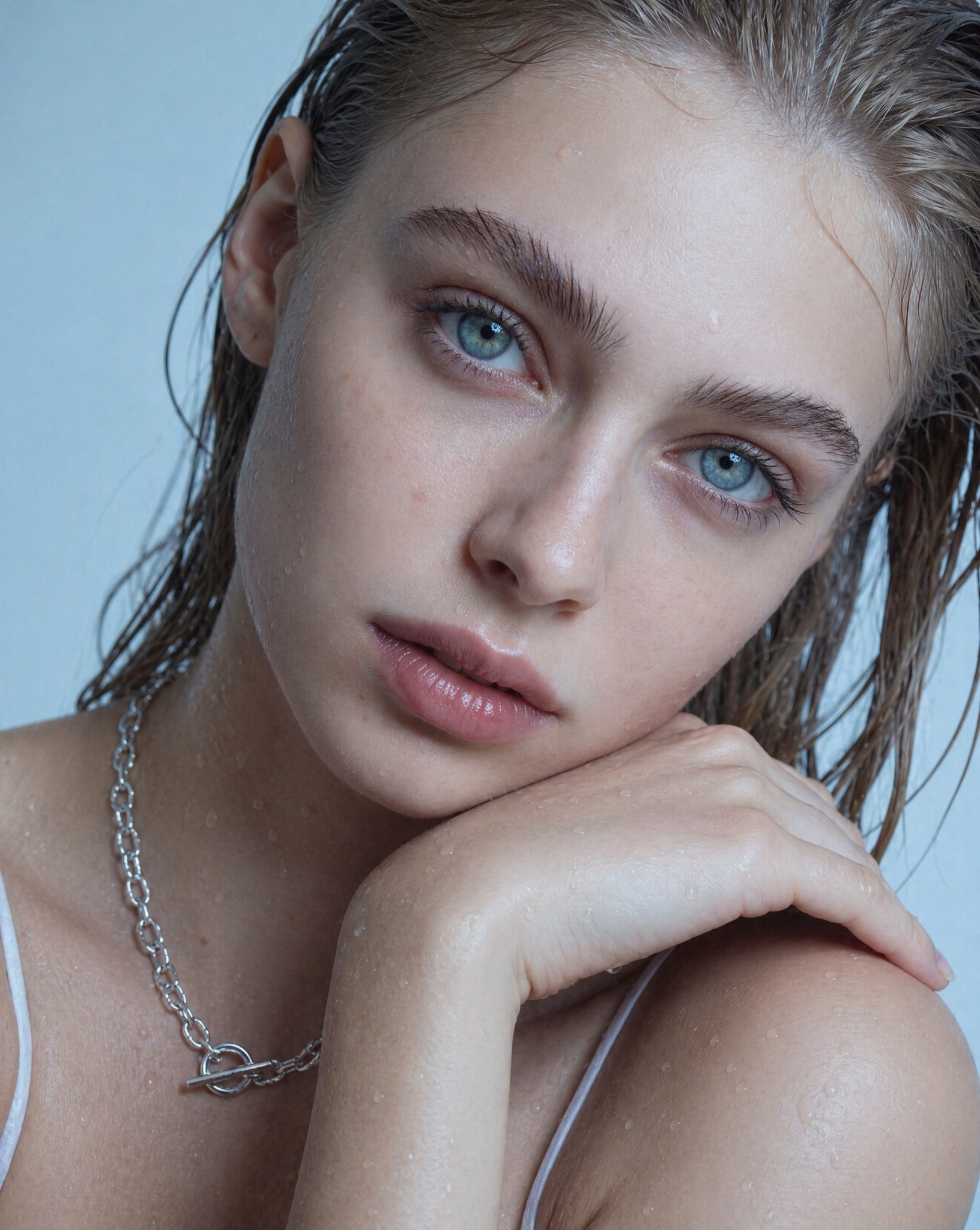 Delicate silver necklace worn by a woman on a neutral background