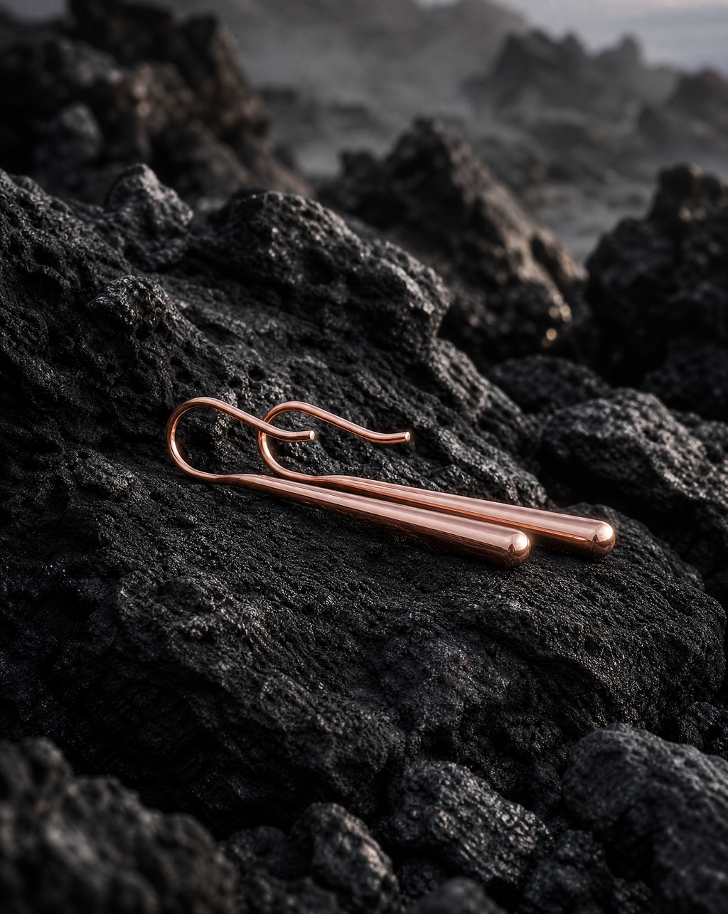 Refined Rose gold drop earrings on a dark, textured surface