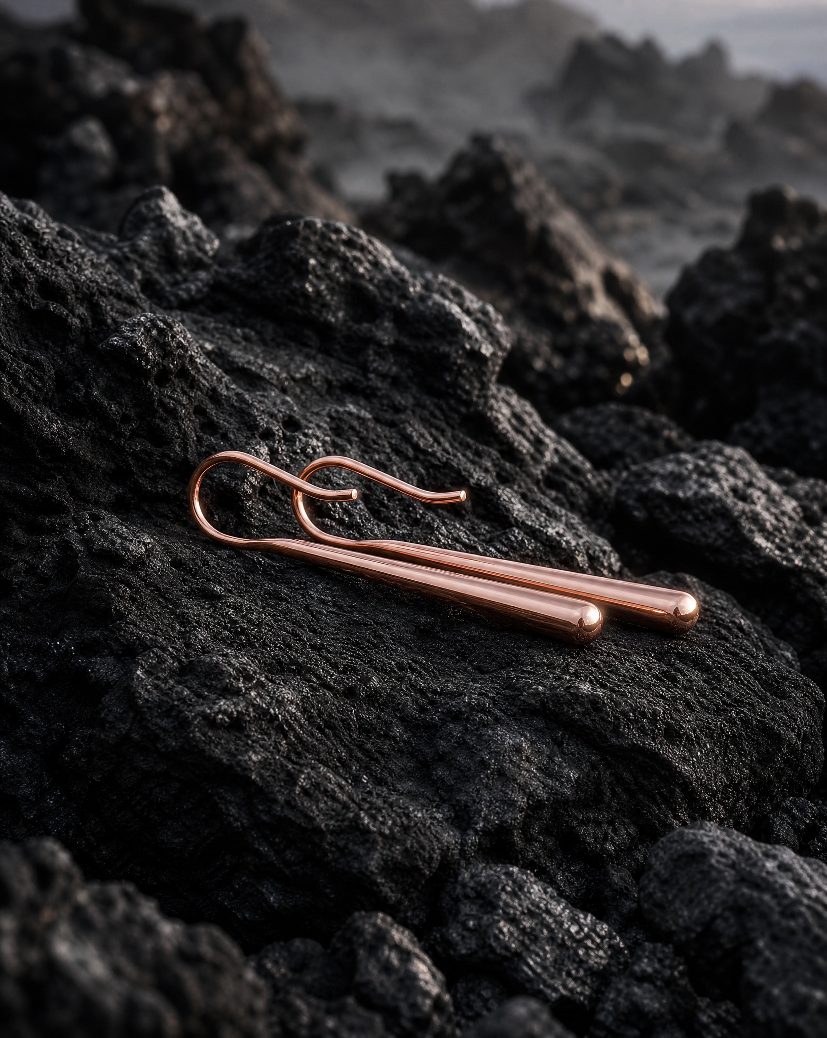 Refined Rose gold drop earrings on a dark, textured surface