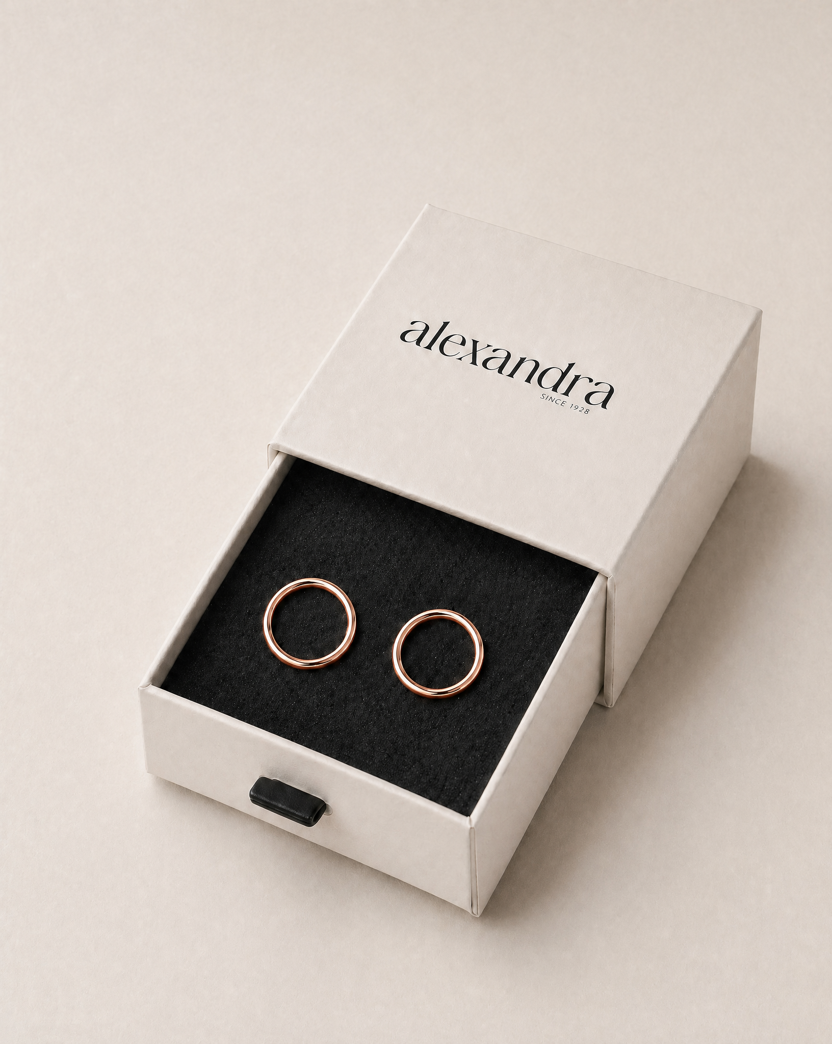 Refined rose gold earrings in a white box with 'alexandra' branding on a light beige background