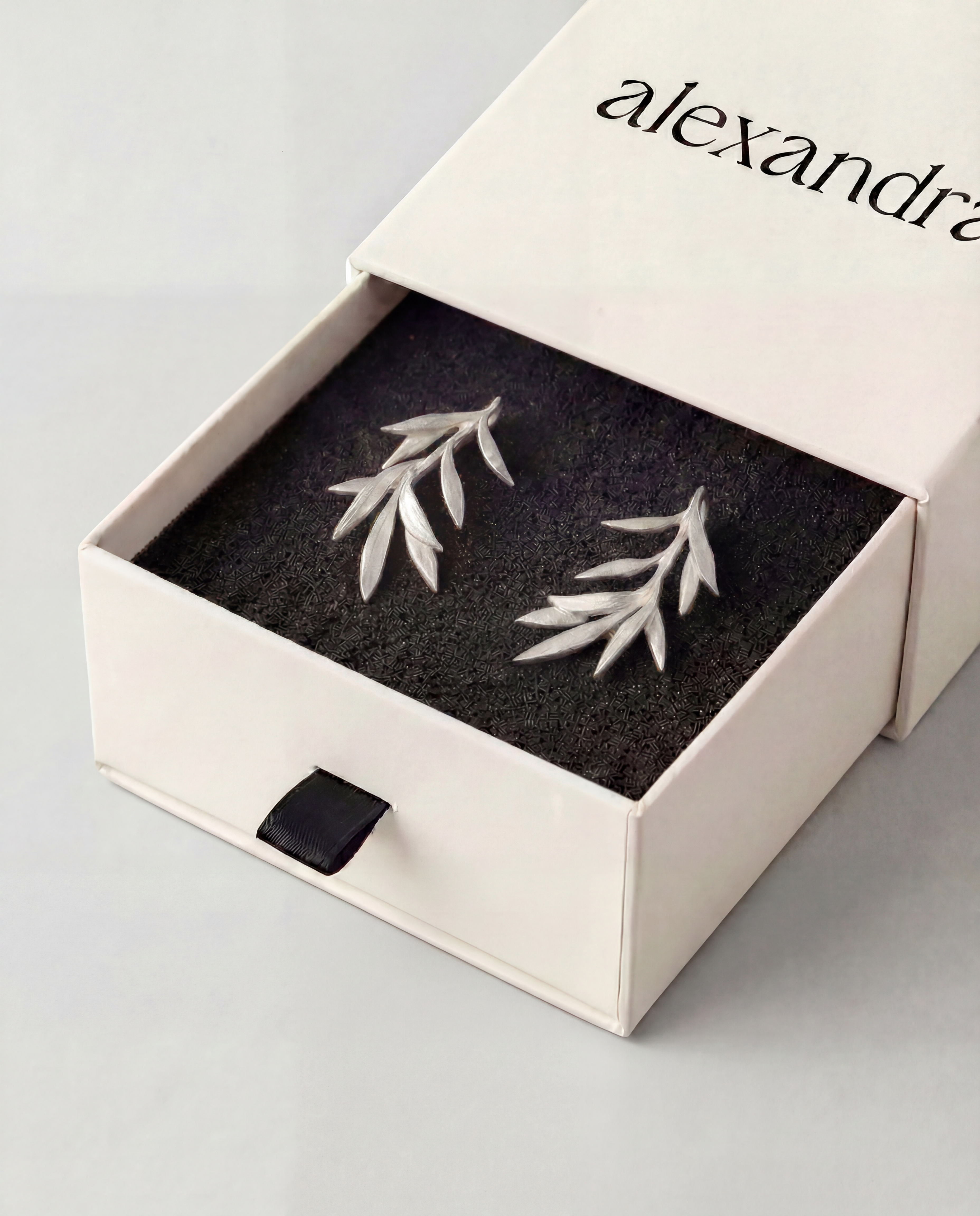 Sculptured Silver leaf earrings in a "alexandra" branded box on a light grey background