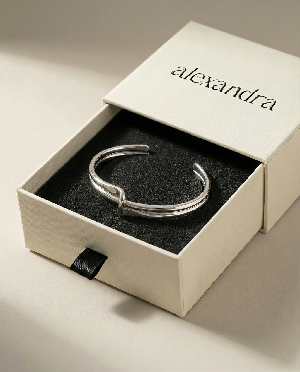 Silver bracelet in a 'alexandra' branded box on a neutral background