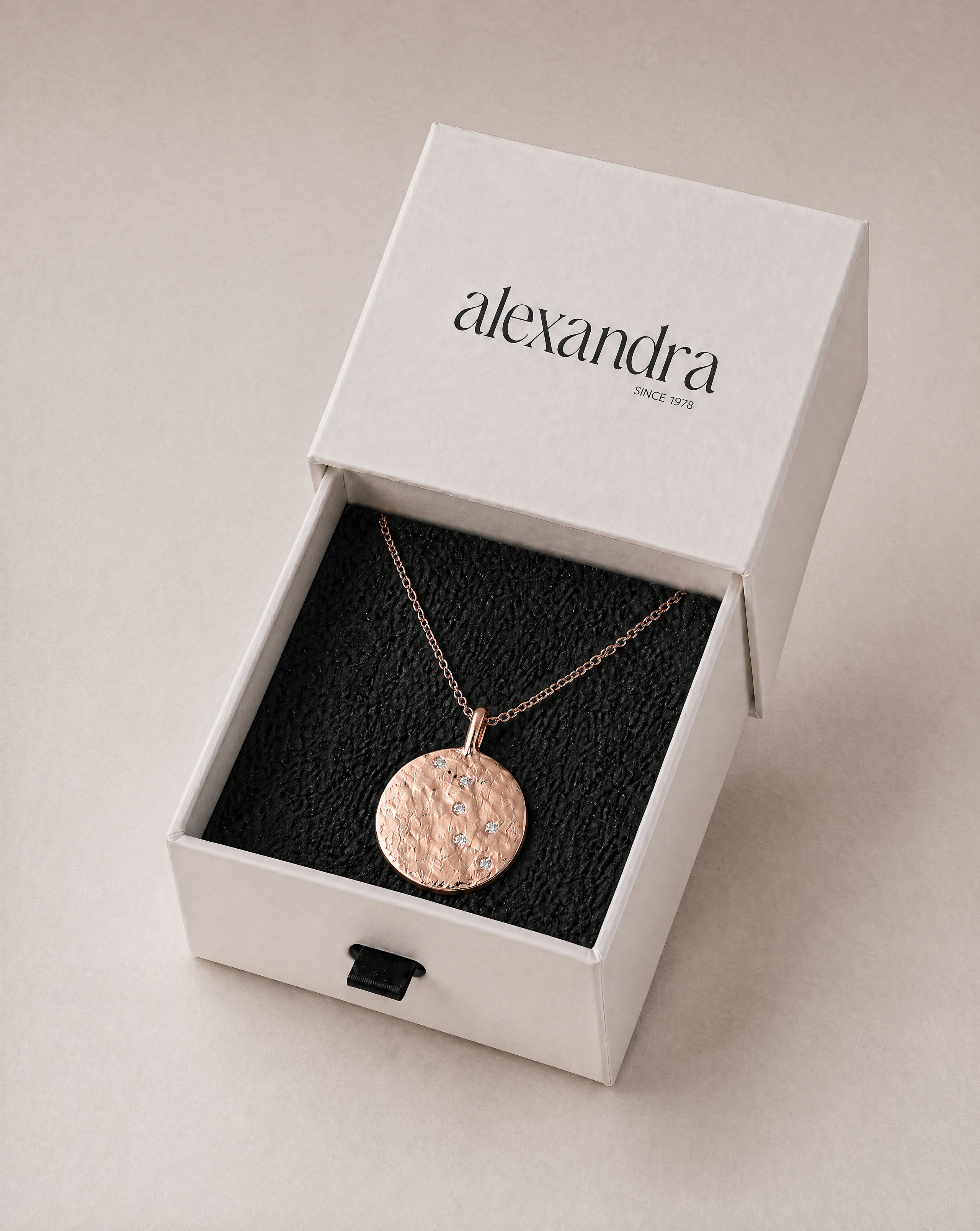 Sculptured Rose gold necklace in a 'alexandra' branded box on a beige background
