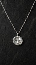 Refined Silver necklace with a textured stone set pendant on a dark background