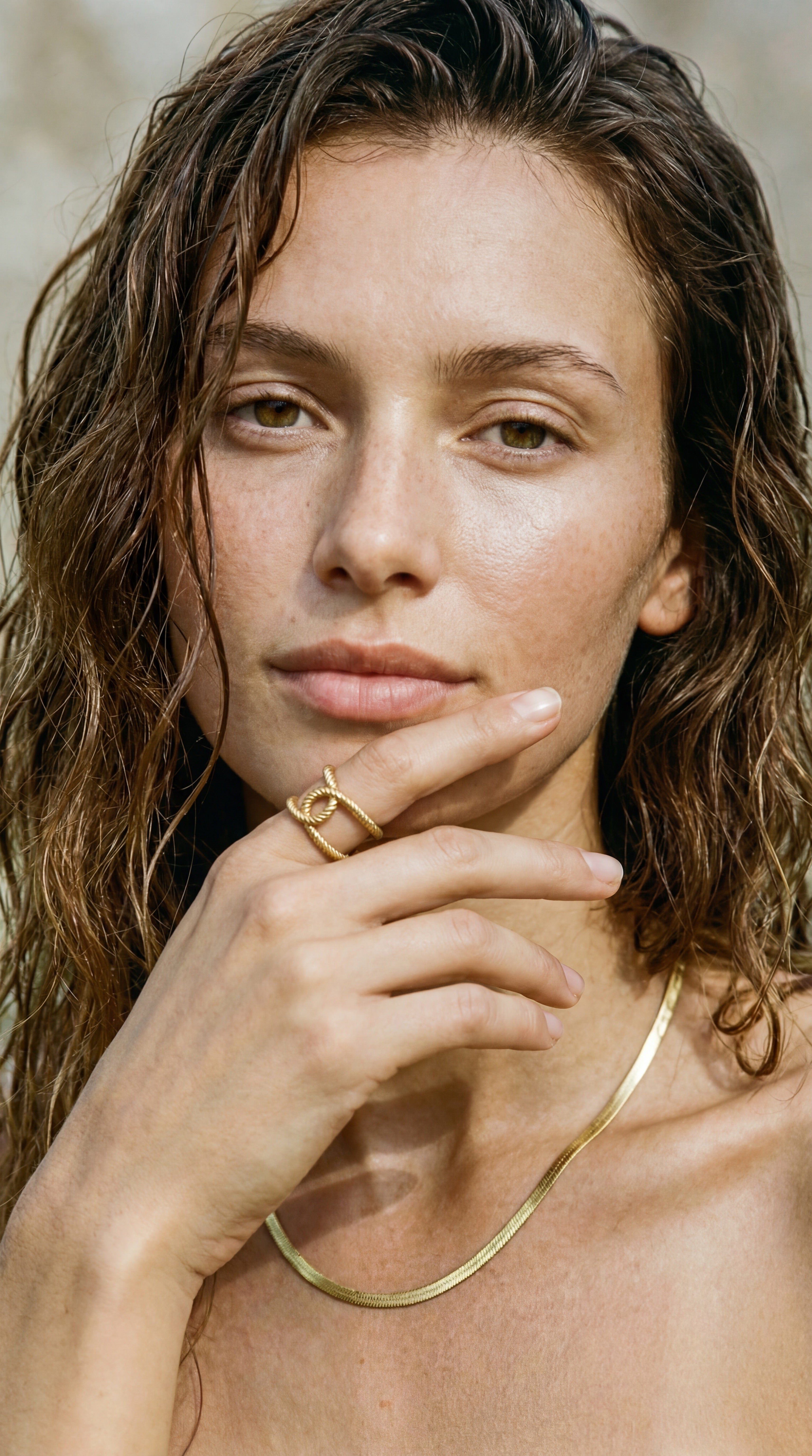 Woman wearing an architectural gold ring with a neutral background