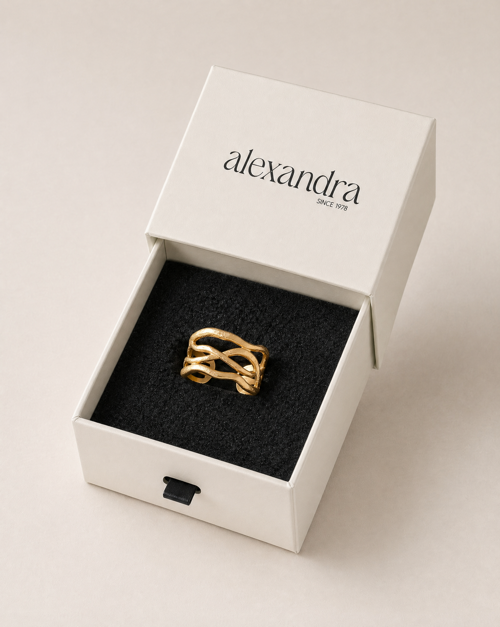 Textured gold ring in a white box with 'alexandra' branding on a light background