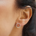 Woman wearing a sculptural silver stud earring on a blurred background