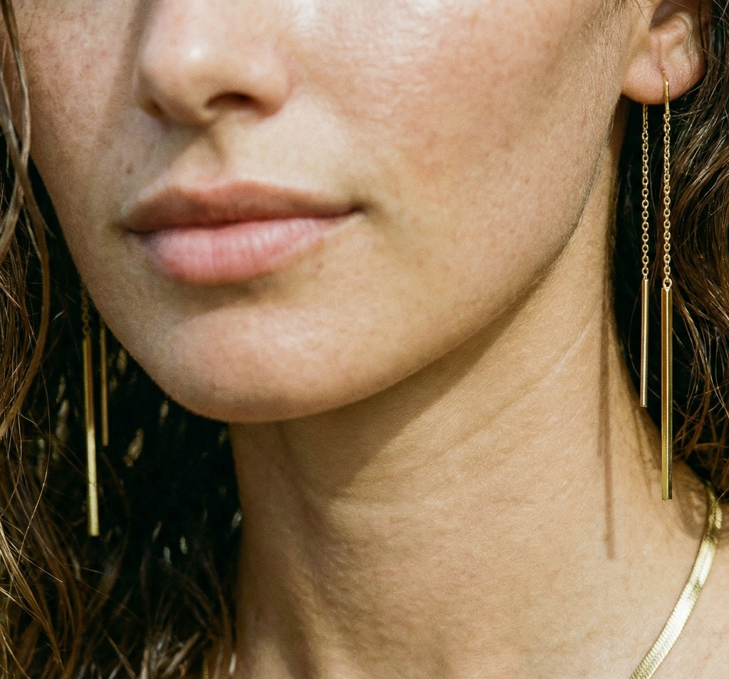 Close-up of a woman wearing delicate gold strand earrings.