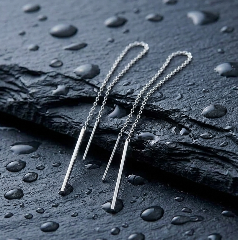 Delicate minimalist silver thread earrings on a dark stone surface 