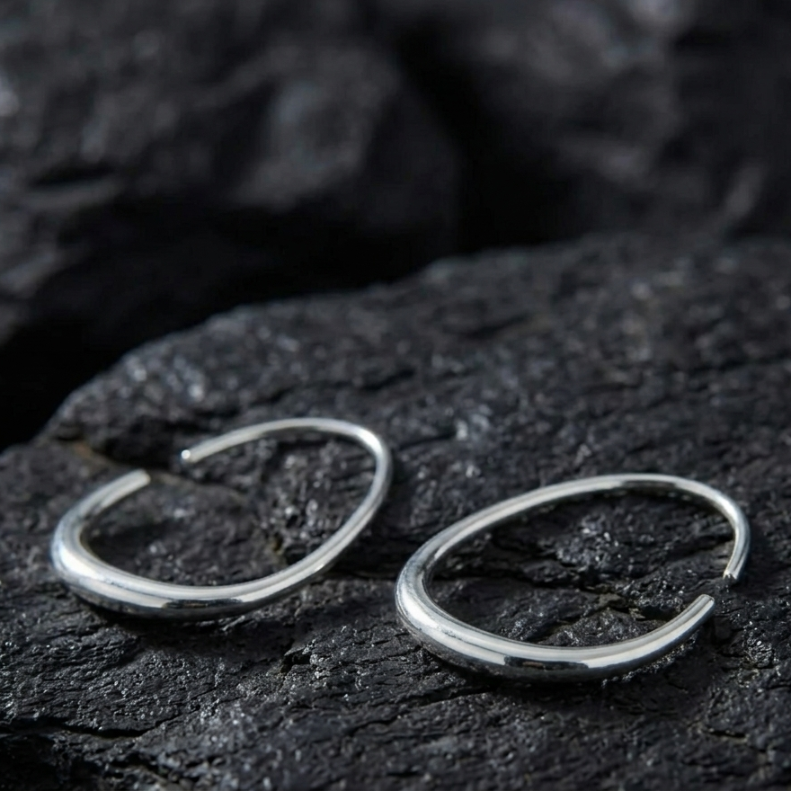 Architectural Silver open hoop earrings on a dark stone surface