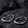 Architectural Silver open hoop earrings on a dark stone surface