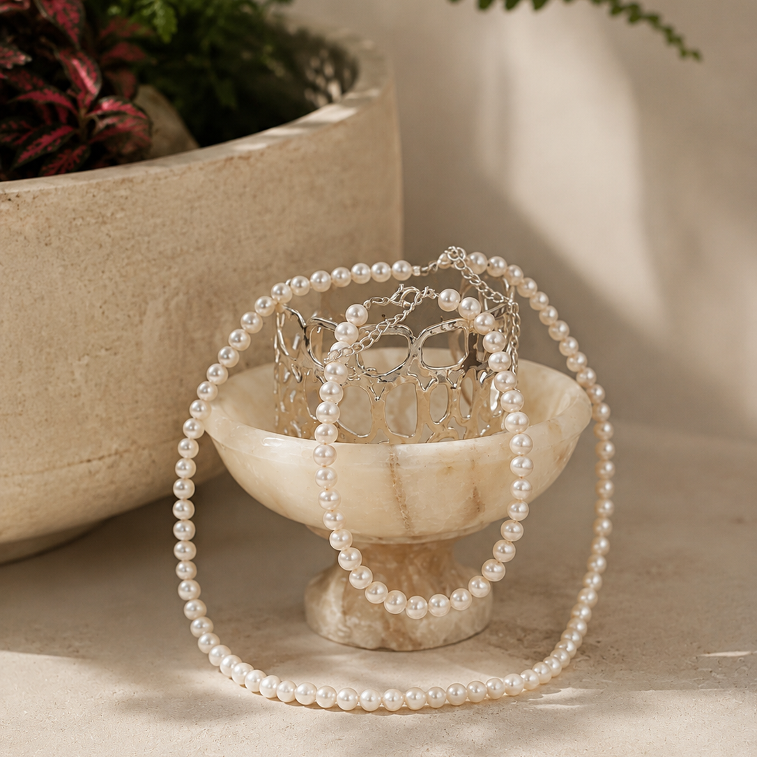 A silver cuff with pearl necklace and bracelet in the morning sun.