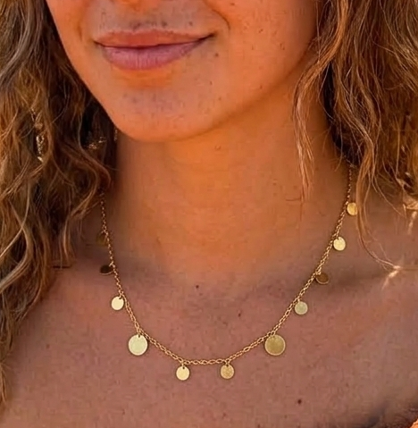 Close-up of a woman wearing a delicate gold necklace with circular pendants.