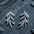 Refined Silver olive branch-shaped earrings on a dark stone surface