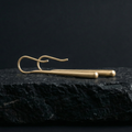 Pair of polished gold earrings on a dark stone surface with a black background